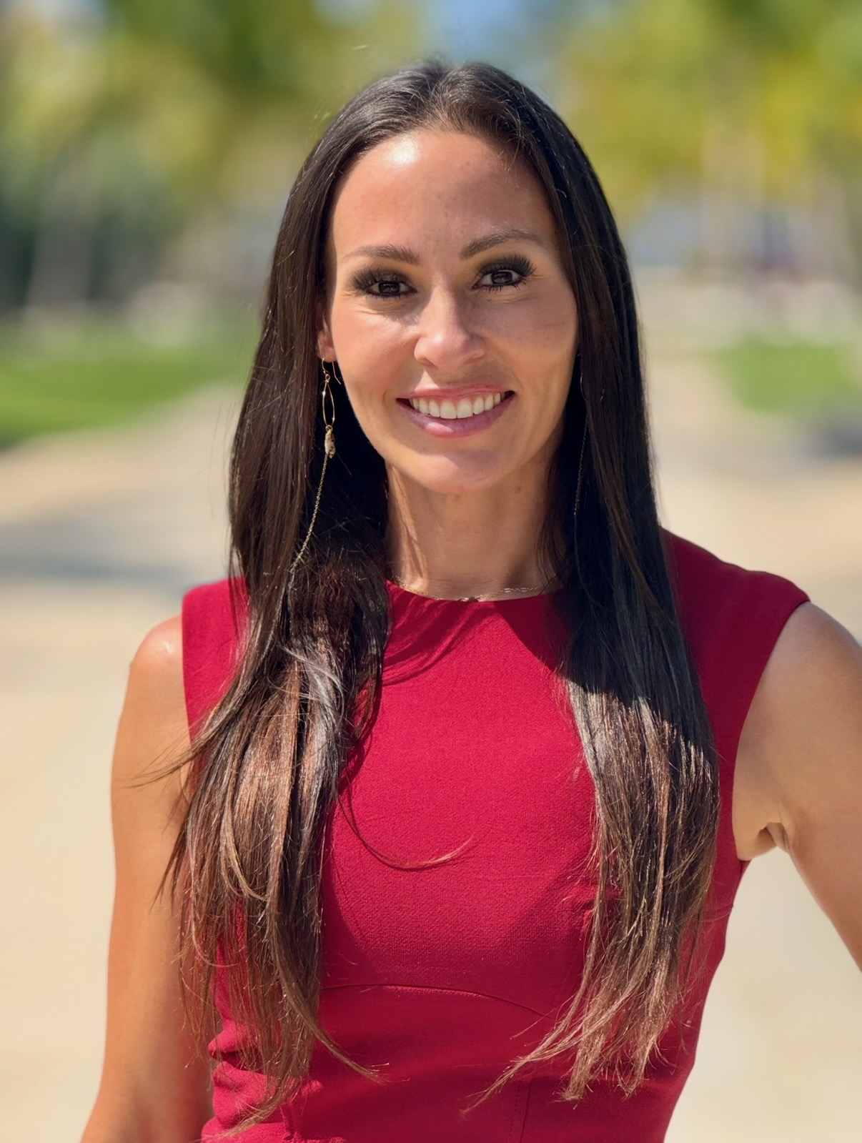 Kanani Ching, AI systems advisor, smiling outdoors in a red dress